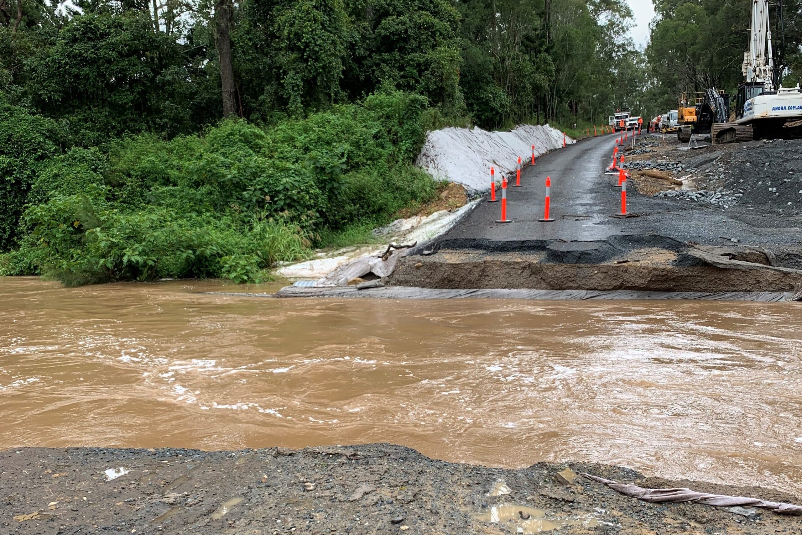 Flying Fox creek Canungra in full flood during Feb 2022 floods. The causeway has been washed away and the creek is high, over its banks and flowing fast. 