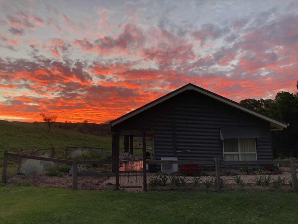 Country Miles Escape cabin with vibrant orange and red sunset behind it.