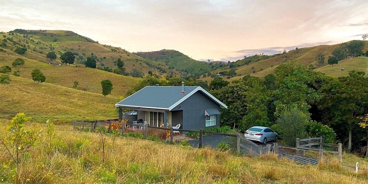 The Shay, an adults-only cottage standing alone among trees with a pink sunset over the rolling hills