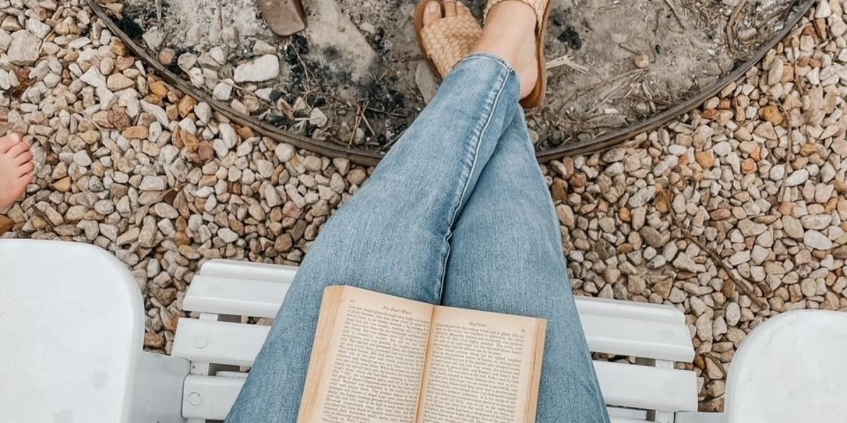 A book resting open on the lap of a guest sitting in a white chair, taking in the country view at Country Mile Escape