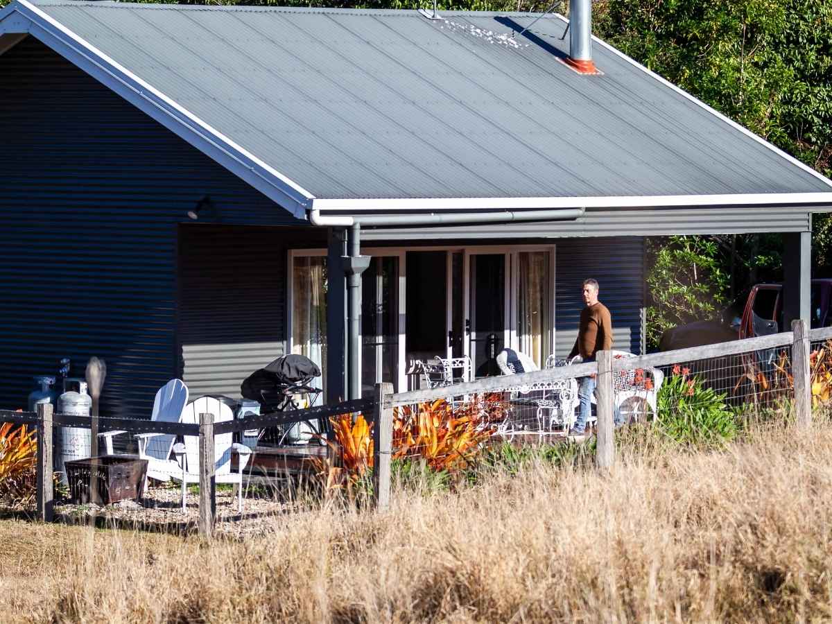 A man taking in the surrounds from the verandah of The Shay cottage at Country Mile Escape