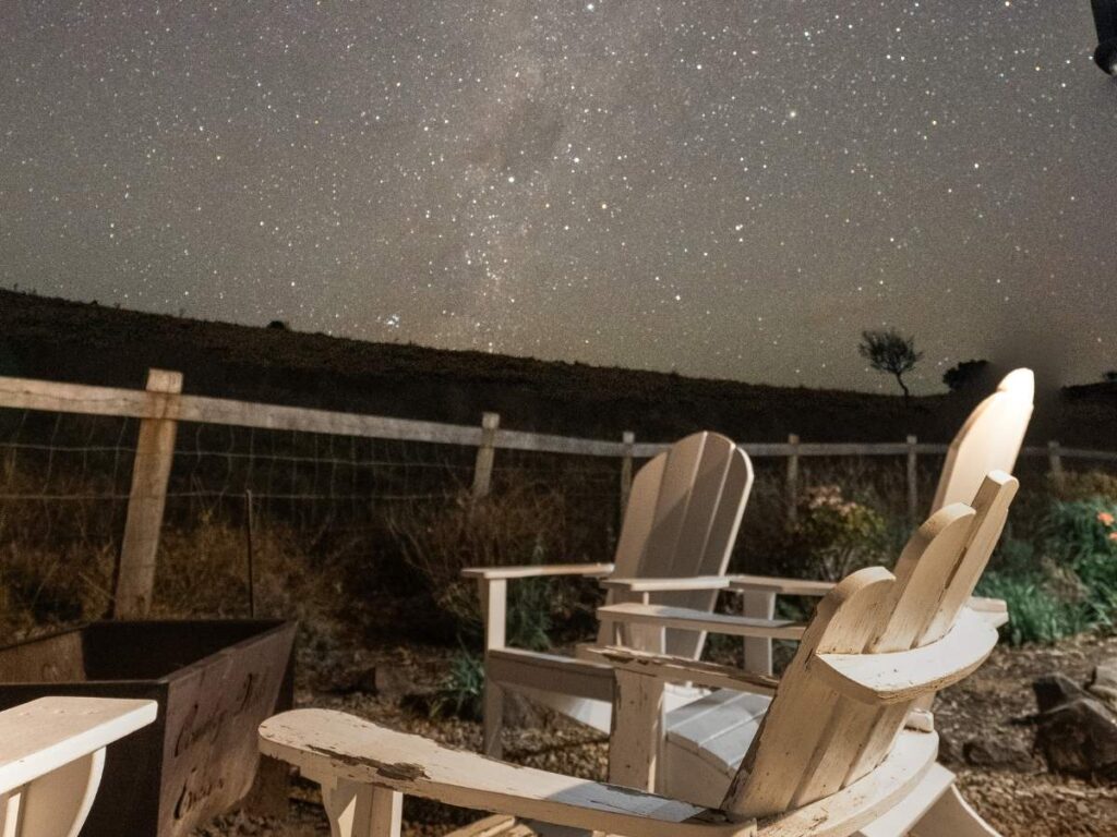 White chairs around a fire pit under a starry night sky at Country Mile Escape in the Scenic Rim
